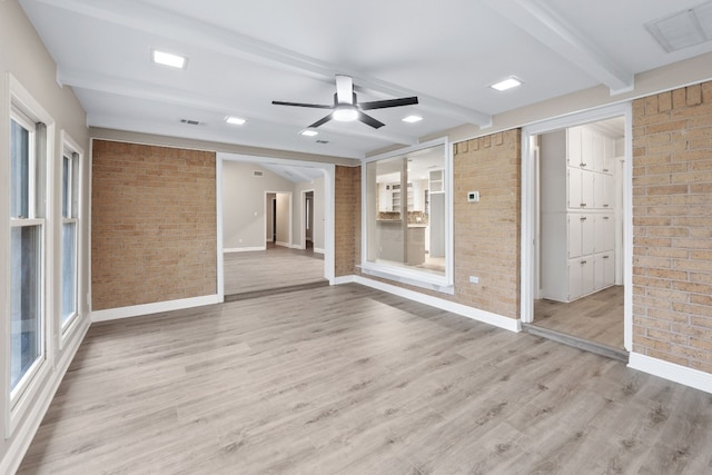 empty room featuring ceiling fan, light hardwood / wood-style floors, beam ceiling, and brick wall