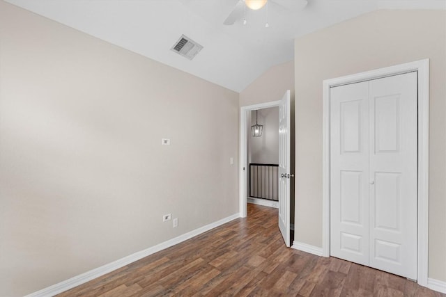 unfurnished bedroom featuring ceiling fan, a closet, dark wood-type flooring, and vaulted ceiling