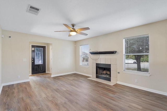 unfurnished living room with a tile fireplace, hardwood / wood-style floors, plenty of natural light, and ceiling fan