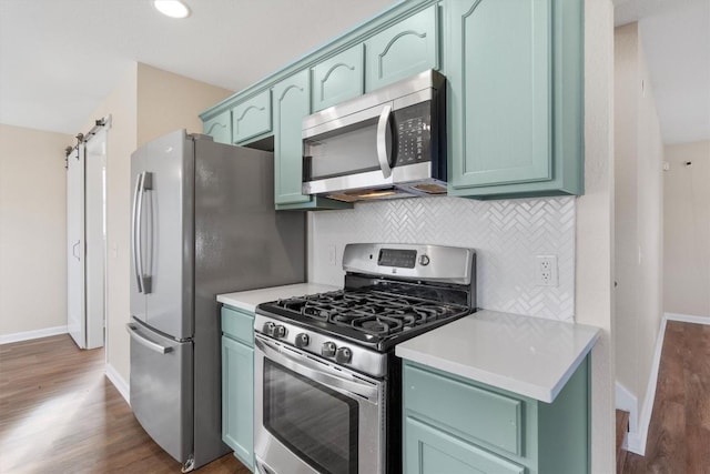 kitchen with dark hardwood / wood-style flooring, a barn door, stainless steel appliances, and green cabinets