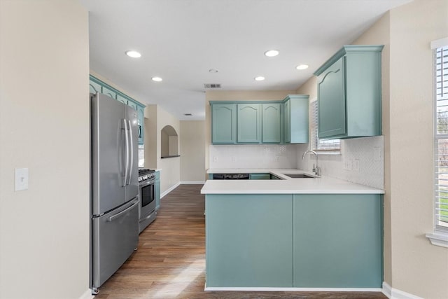 kitchen featuring backsplash, sink, dark hardwood / wood-style flooring, kitchen peninsula, and stainless steel appliances