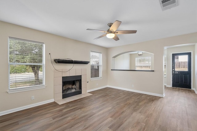 unfurnished living room featuring a tiled fireplace, ceiling fan, and hardwood / wood-style flooring