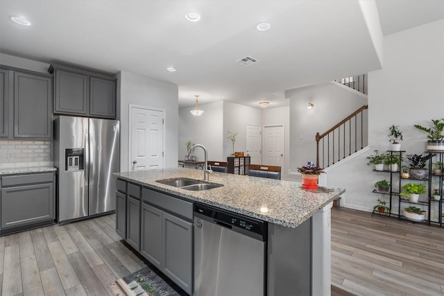 kitchen featuring gray cabinets, a kitchen island with sink, sink, and appliances with stainless steel finishes