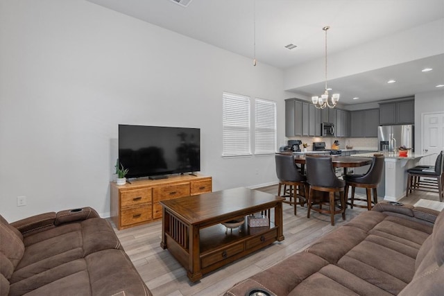 living room featuring light wood-type flooring and a notable chandelier