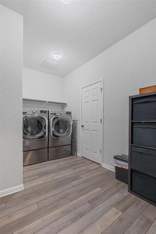 clothes washing area featuring washer and clothes dryer and light hardwood / wood-style floors