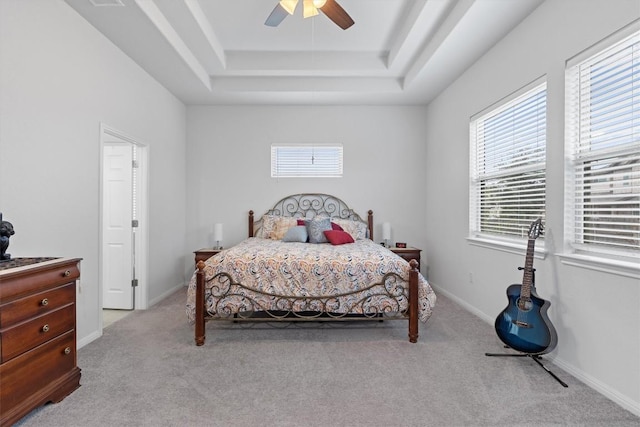 bedroom with light carpet, a raised ceiling, and ceiling fan