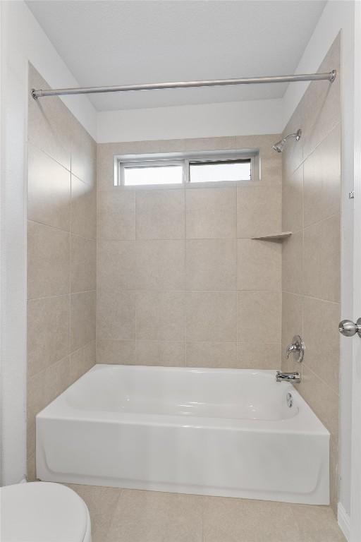 bathroom featuring tiled shower / bath combo and toilet