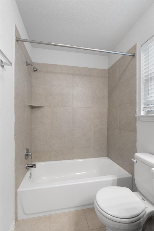 bathroom with tile patterned floors, tiled shower / bath combo, and toilet