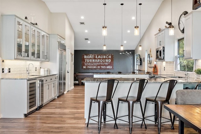 kitchen featuring appliances with stainless steel finishes, white cabinetry, kitchen peninsula, and light stone countertops