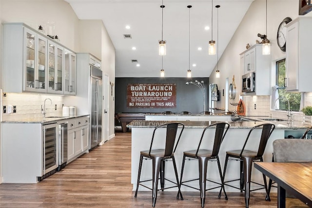 106 Center Cove Ii Loop, Spicewood, TX 78669 - kitchen with a peninsula, appliances with stainless steel finishes, beverage cooler, a sink, and light stone counters