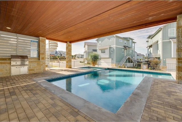 view of swimming pool featuring an outdoor kitchen, a patio, and grilling area