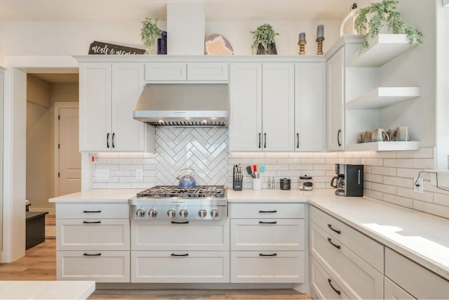 kitchen featuring white cabinetry, wall chimney exhaust hood, tasteful backsplash, light hardwood / wood-style floors, and stainless steel gas stovetop