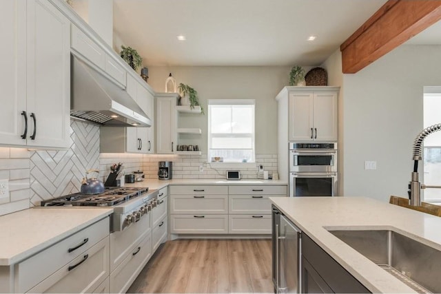 kitchen with appliances with stainless steel finishes, tasteful backsplash, sink, light hardwood / wood-style flooring, and white cabinets