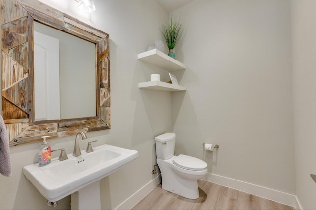 bathroom with toilet, wood-type flooring, and sink