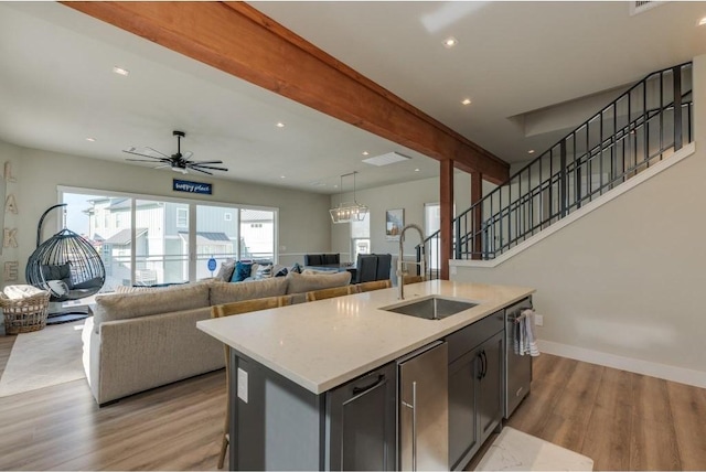 kitchen with sink, ceiling fan, an island with sink, light hardwood / wood-style floors, and stainless steel appliances