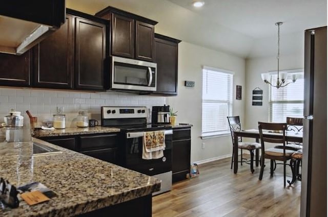 kitchen featuring appliances with stainless steel finishes, pendant lighting, tasteful backsplash, light hardwood / wood-style floors, and dark brown cabinets