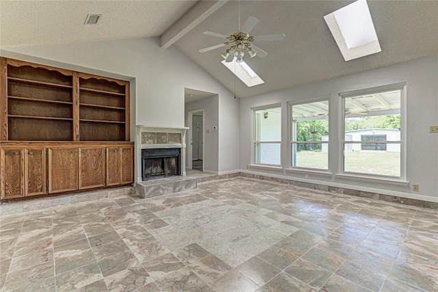 unfurnished living room featuring a skylight, ceiling fan, a tile fireplace, high vaulted ceiling, and beamed ceiling