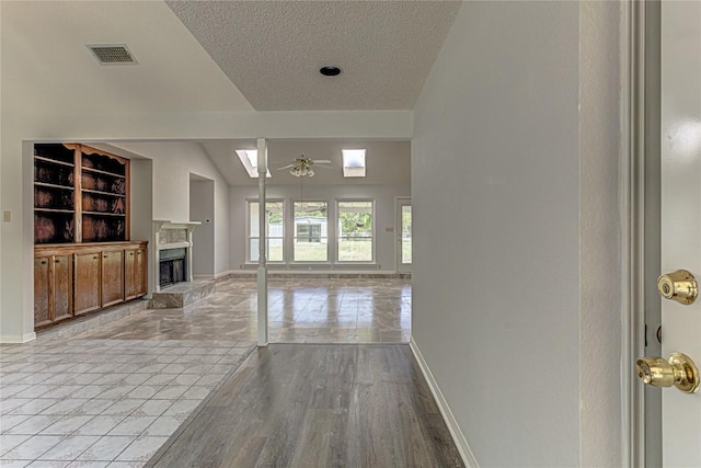 unfurnished living room with ceiling fan, light wood-type flooring, and a textured ceiling