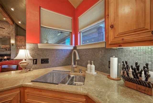 kitchen featuring lofted ceiling with beams, a large fireplace, tasteful backsplash, and sink