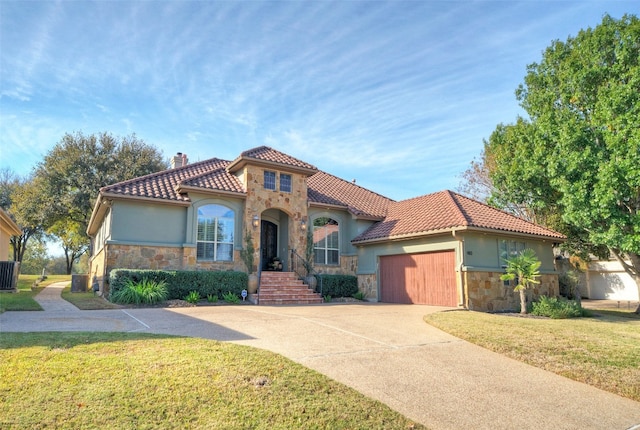 mediterranean / spanish house with central air condition unit, a front lawn, and a garage