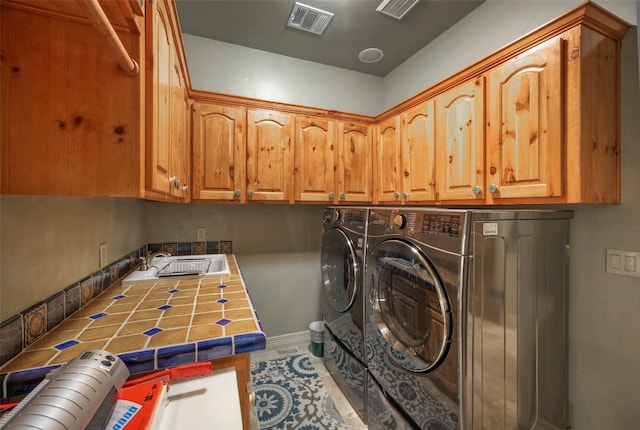 laundry room featuring washer and clothes dryer, sink, and cabinets