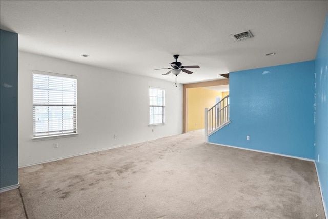 carpeted spare room featuring ceiling fan and a wealth of natural light