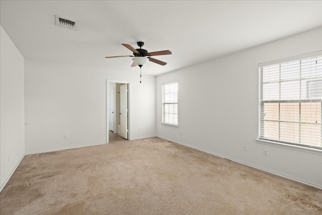 carpeted empty room with ceiling fan and plenty of natural light