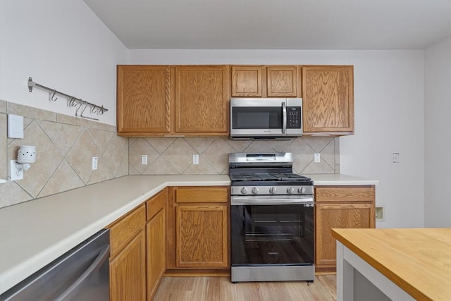 kitchen featuring stainless steel appliances, tasteful backsplash, and light wood-type flooring