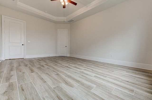 empty room featuring ceiling fan, a raised ceiling, ornamental molding, and light hardwood / wood-style flooring