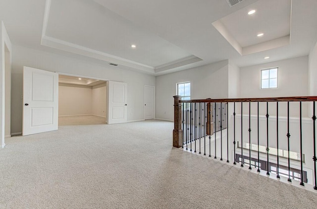 carpeted spare room with a raised ceiling