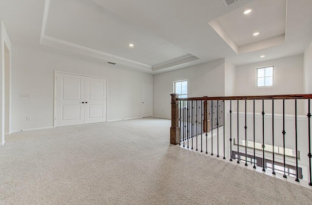 carpeted spare room with a raised ceiling