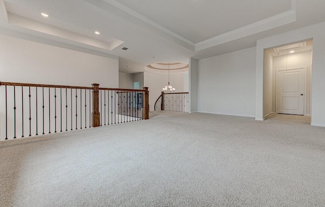 carpeted empty room with an inviting chandelier, a raised ceiling, and crown molding