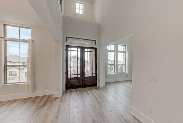 foyer with a wealth of natural light, french doors, a high ceiling, and light hardwood / wood-style flooring