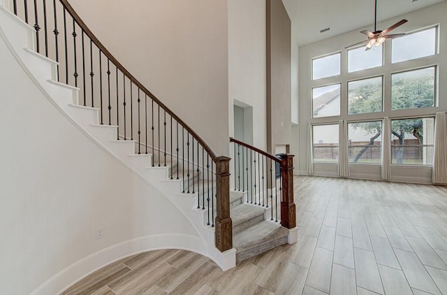 stairway featuring a towering ceiling, hardwood / wood-style flooring, and a healthy amount of sunlight