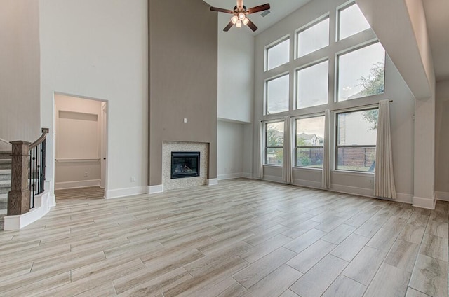 unfurnished living room featuring a high ceiling, light hardwood / wood-style floors, and ceiling fan