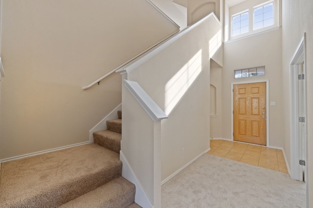 foyer entrance with light carpet and a high ceiling