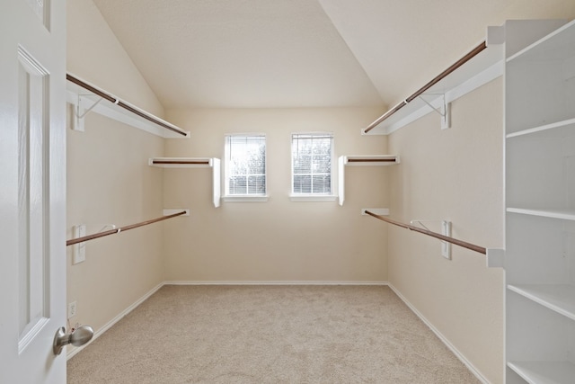 walk in closet with light colored carpet and vaulted ceiling