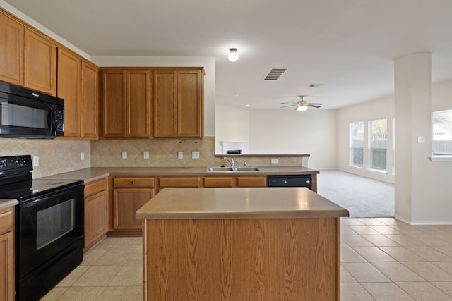 kitchen featuring black appliances, a kitchen island, light tile patterned floors, and sink