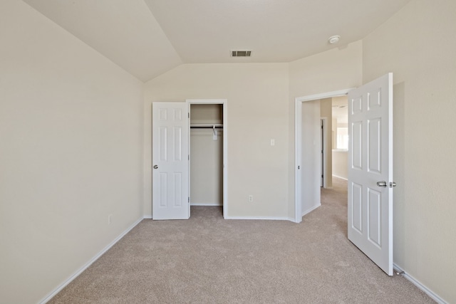 unfurnished bedroom featuring a closet, light carpet, and vaulted ceiling