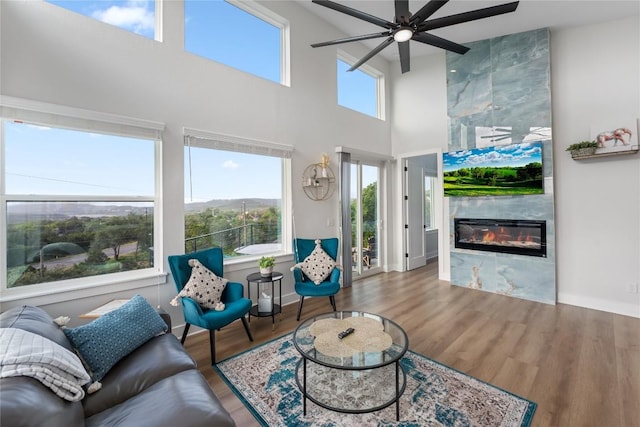 living room featuring a tiled fireplace, ceiling fan, hardwood / wood-style floors, and a healthy amount of sunlight