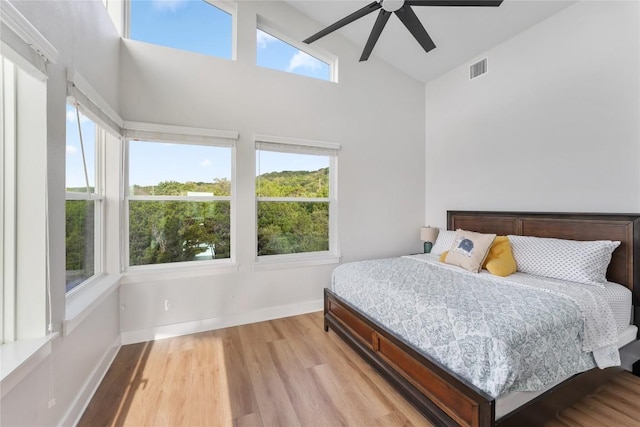 bedroom featuring ceiling fan, high vaulted ceiling, and light hardwood / wood-style flooring