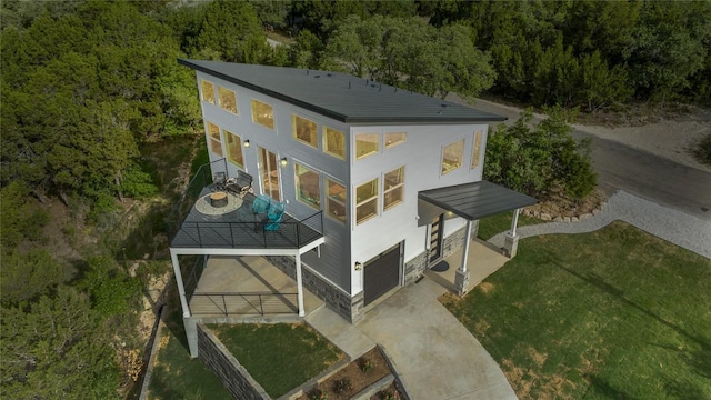 rear view of house featuring a garage, a yard, and a balcony