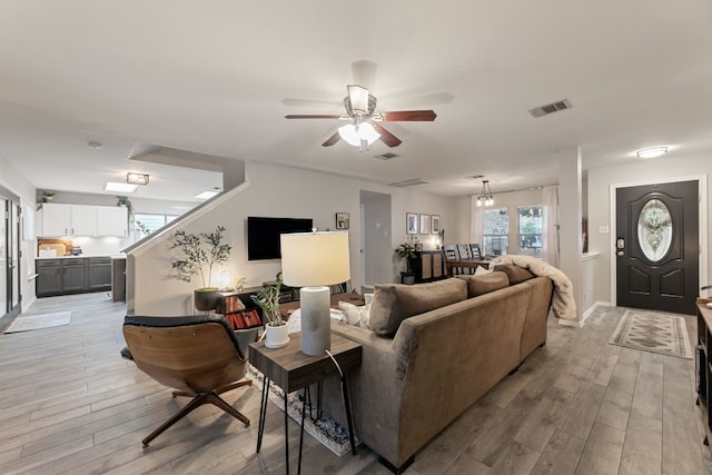 living room featuring ceiling fan with notable chandelier and light hardwood / wood-style floors