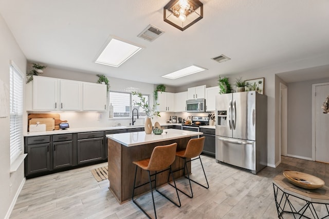 kitchen featuring appliances with stainless steel finishes, a kitchen island, a wealth of natural light, and a kitchen breakfast bar