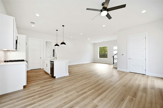 kitchen featuring white cabinets, sink, hanging light fixtures, and a kitchen island with sink