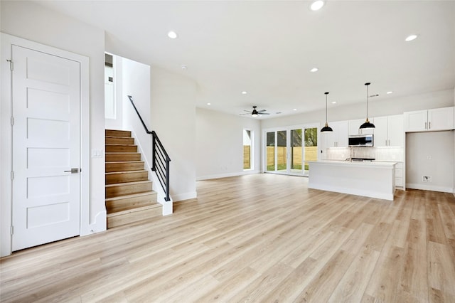 unfurnished living room with ceiling fan and light hardwood / wood-style flooring