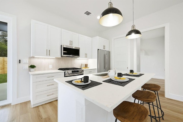 102 W Fawnridge Dr, Austin, TX 78753 - kitchen featuring stainless steel appliances, light wood finished floors, light countertops, tasteful backsplash, and white cabinetry