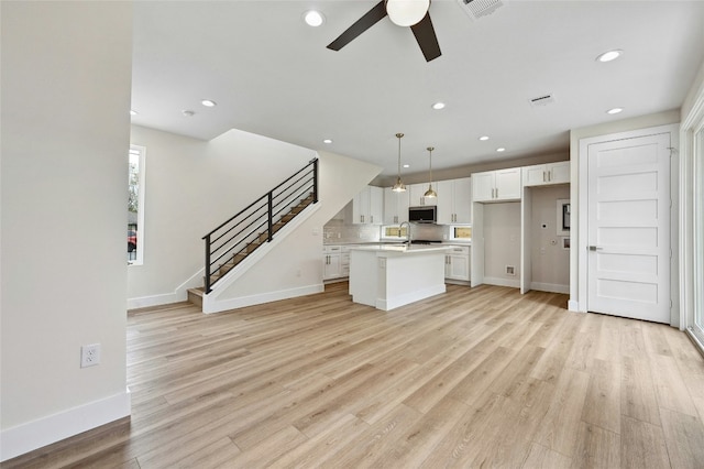 9104 Georgian Dr, Austin, TX 78753 - unfurnished living room with a ceiling fan, recessed lighting, light wood finished floors, and stairs
