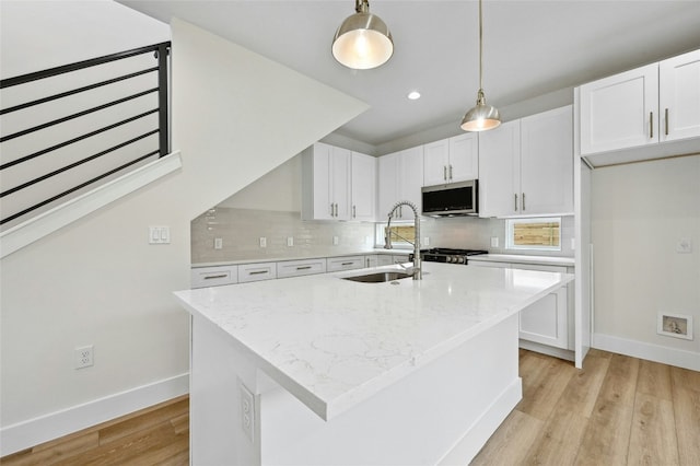 kitchen with white cabinets, pendant lighting, sink, and an island with sink