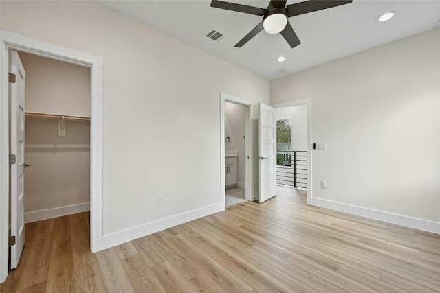 unfurnished bedroom with a walk in closet, ensuite bath, ceiling fan, light hardwood / wood-style floors, and a closet